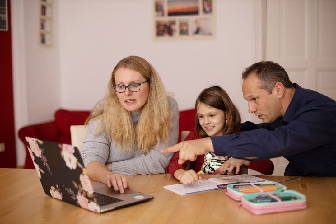 Vuxna och barn samlas kring en laptop och skolmaterial vid ett bord
