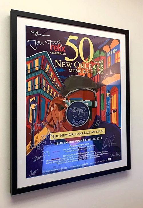 En inramad affisch med färgstark grafik, text och flera signaturer.